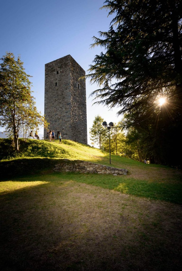 una torre di pietra su una collina con persone che vi camminano intorno