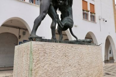 una statua di un uomo con un leone su un piedistallo di pietra