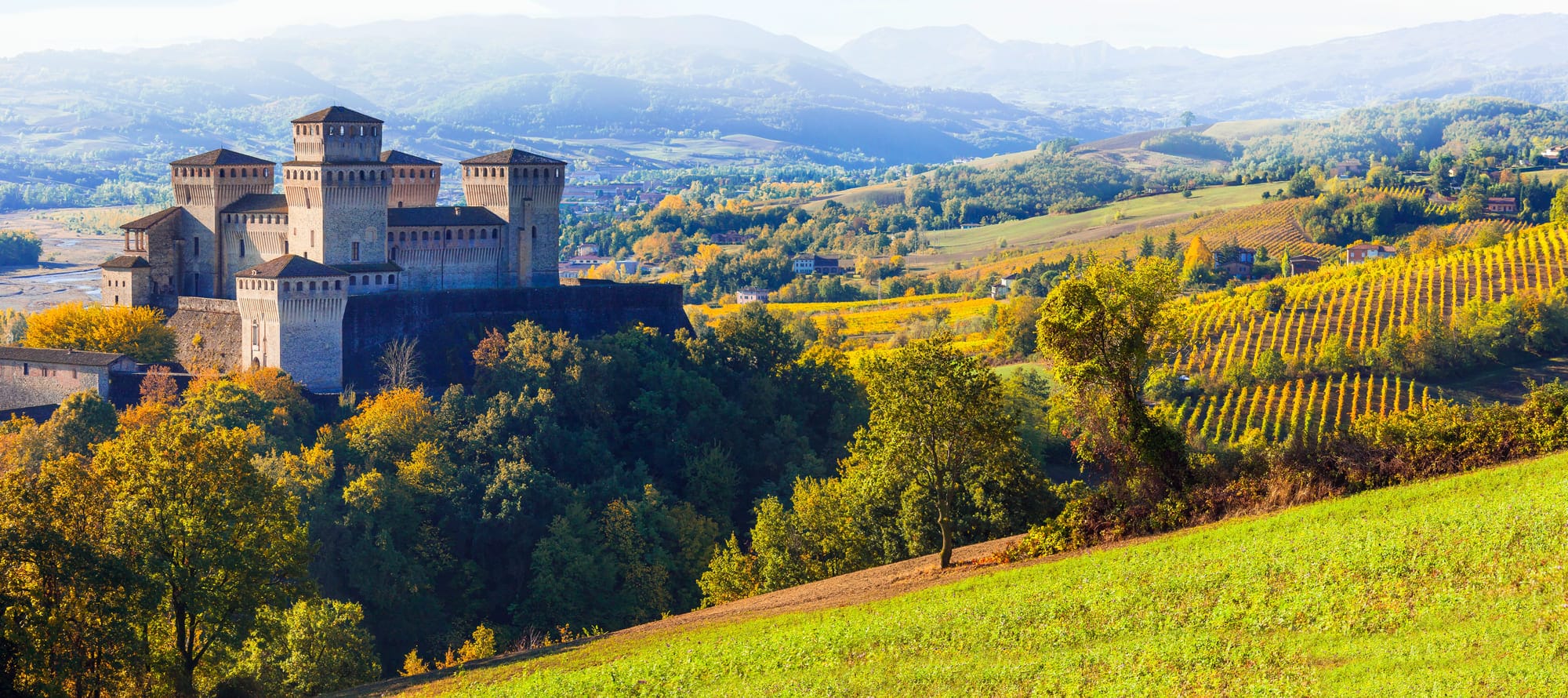 un castello su una collina con alberi e montagne sullo sfondo