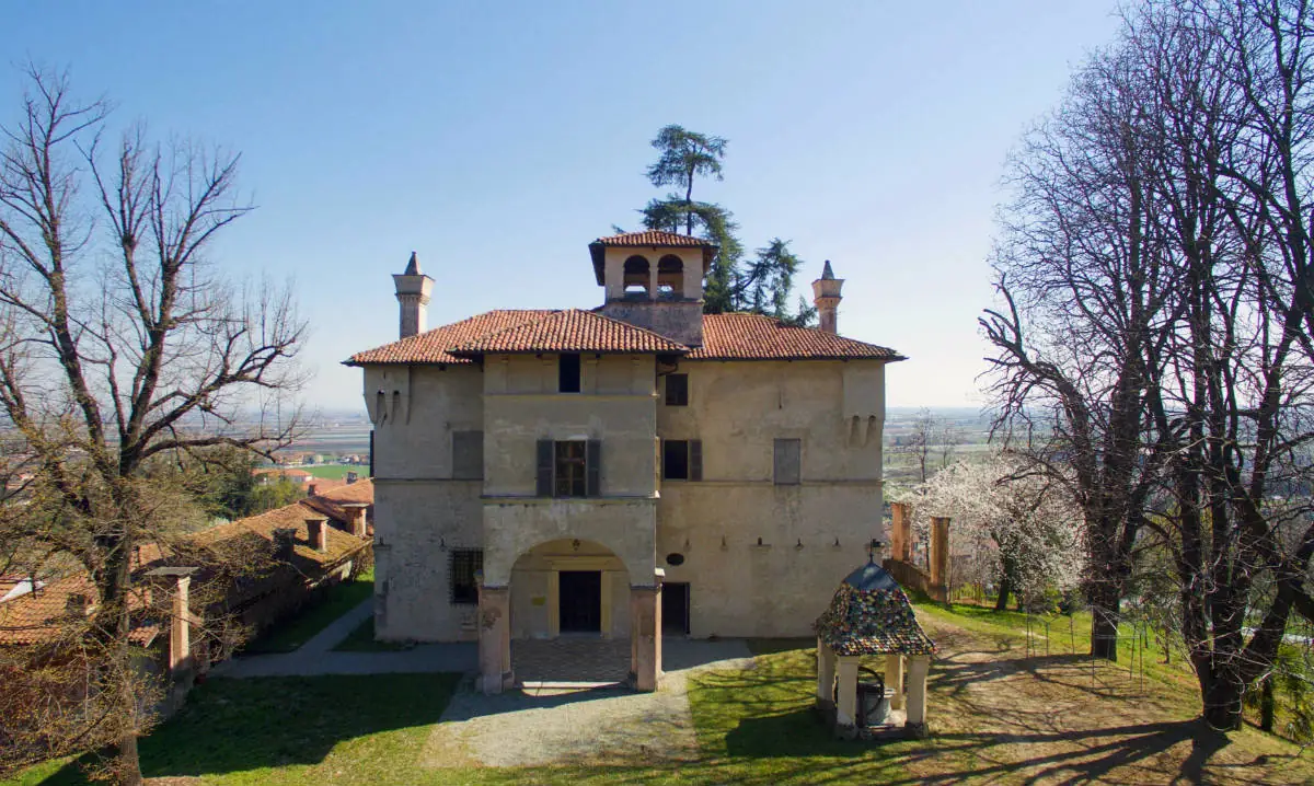 un grande edificio con un pozzo e degli alberi sullo sfondo