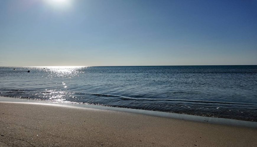 una spiaggia con uno specchio d'acqua e un cielo blu