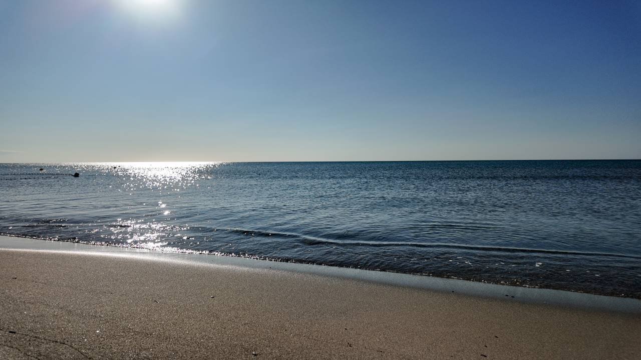 una spiaggia con uno specchio d'acqua e un cielo blu