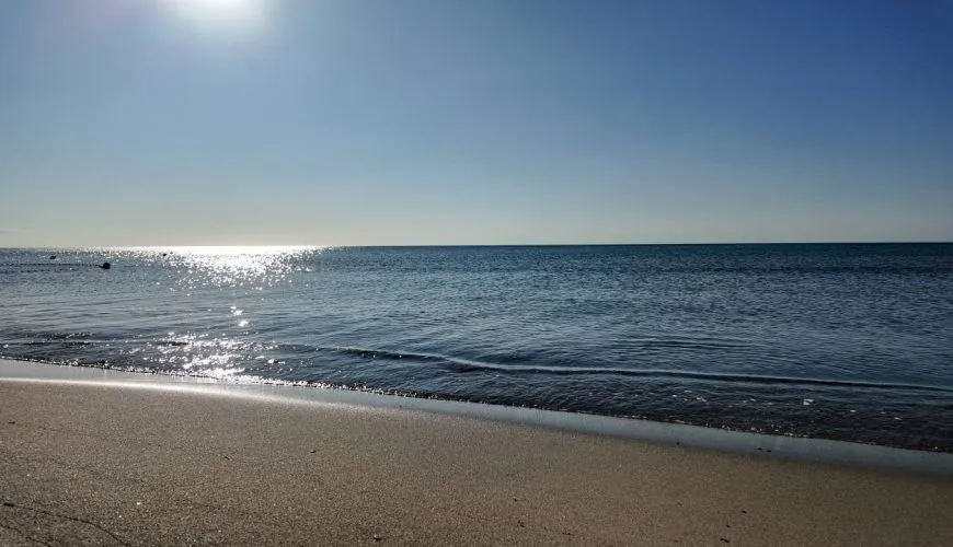 una spiaggia con uno specchio d'acqua e un cielo blu